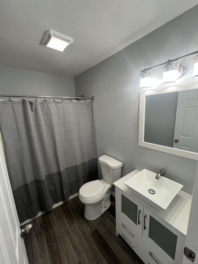 bathroom featuring toilet, curtained shower, wood finished floors, and vanity