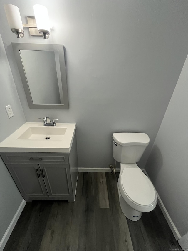 bathroom with toilet, baseboards, wood finished floors, and vanity