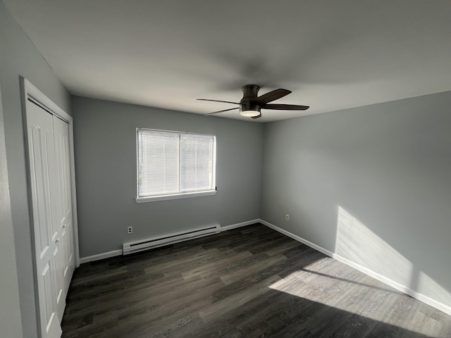 unfurnished bedroom with a baseboard heating unit, a closet, baseboards, and dark wood-style floors