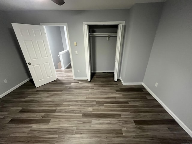 unfurnished bedroom with dark wood-style floors, baseboards, and a closet