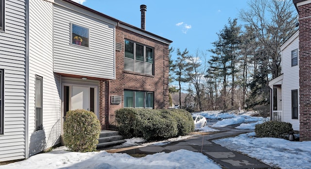 snow covered property featuring brick siding