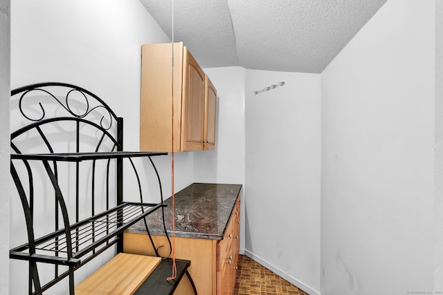 interior space featuring brick floor, baseboards, and a textured ceiling