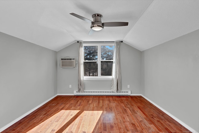 bonus room featuring a baseboard radiator, baseboards, hardwood / wood-style floors, and an AC wall unit