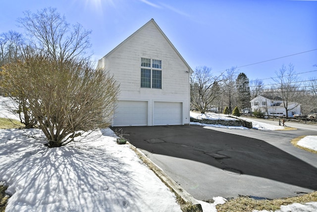 view of snowy exterior featuring aphalt driveway and an attached garage