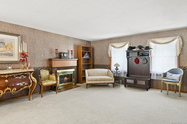 sitting room featuring a textured ceiling, a brick fireplace, carpet flooring, and wallpapered walls