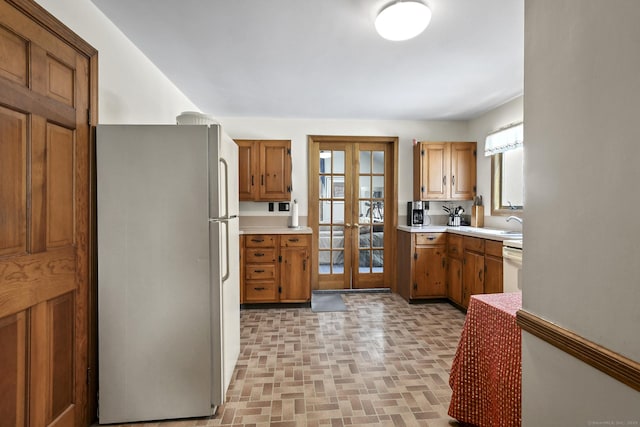 kitchen featuring french doors, a healthy amount of sunlight, freestanding refrigerator, and brown cabinets