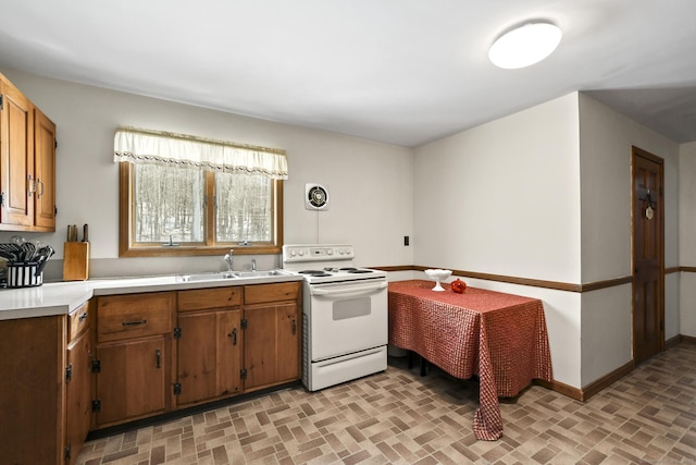 kitchen with white electric stove, baseboards, a sink, light countertops, and brick patterned floor