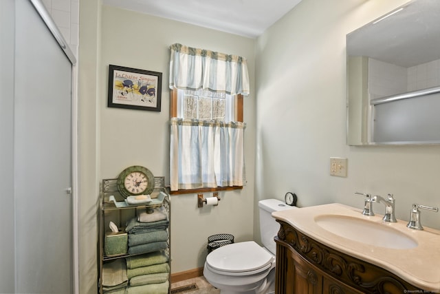 full bath featuring visible vents, toilet, a shower with shower door, vanity, and baseboards