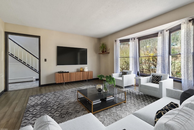 living area featuring baseboards, a textured ceiling, wood finished floors, and baseboard heating