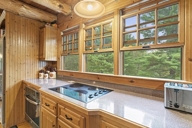 kitchen with wooden ceiling, black electric cooktop, wood walls, stainless steel oven, and beam ceiling