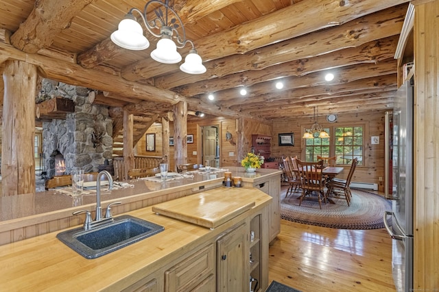 kitchen featuring wooden counters, a sink, a chandelier, beamed ceiling, and hardwood / wood-style floors