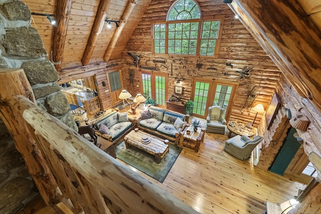 living area featuring high vaulted ceiling, beamed ceiling, wooden ceiling, and rustic walls