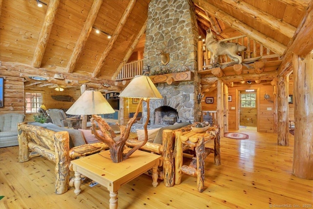 living area with wooden ceiling, wood-type flooring, beamed ceiling, a stone fireplace, and high vaulted ceiling