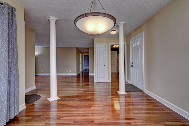 75 Redwood Dr Unit 510, East Haven, CT 06513 - unfurnished dining area with decorative columns, a textured ceiling, baseboards, and wood finished floors