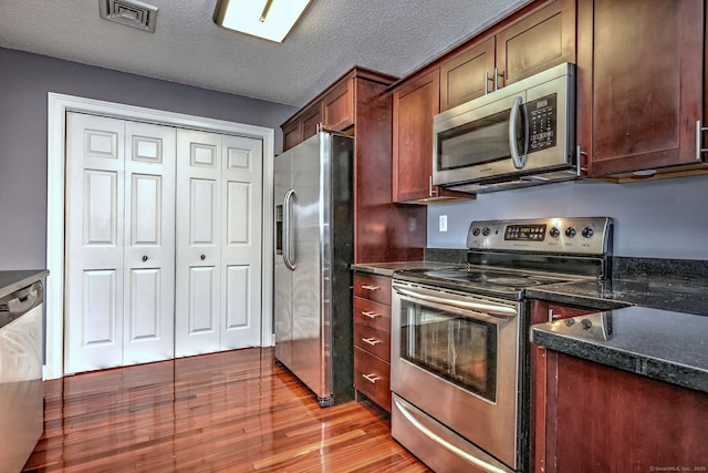 75 Redwood Dr Unit 510, East Haven, CT 06513 - kitchen with visible vents, light wood-style flooring, appliances with stainless steel finishes, a textured ceiling, and dark stone countertops
