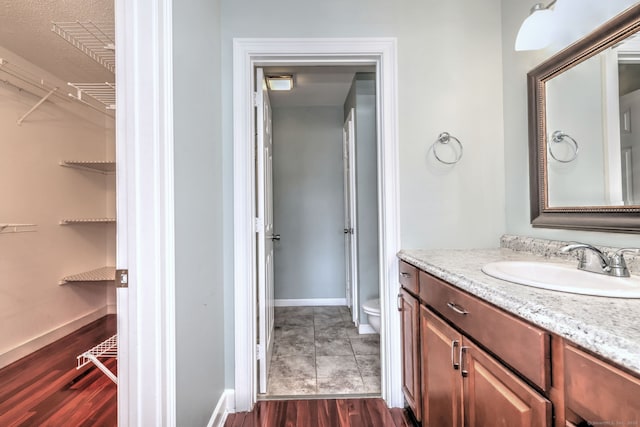 75 Redwood Dr Unit 510, East Haven, CT 06513 - bathroom featuring a walk in closet, toilet, vanity, wood finished floors, and baseboards