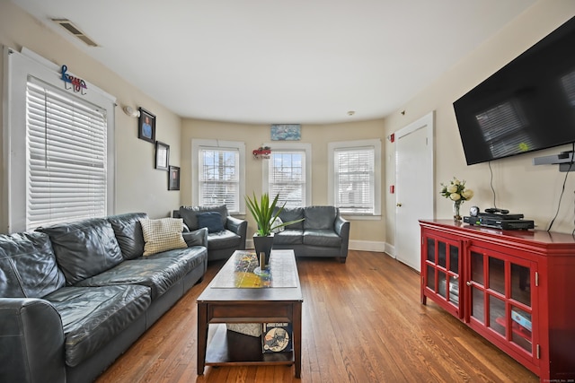 living room with visible vents, baseboards, and wood finished floors