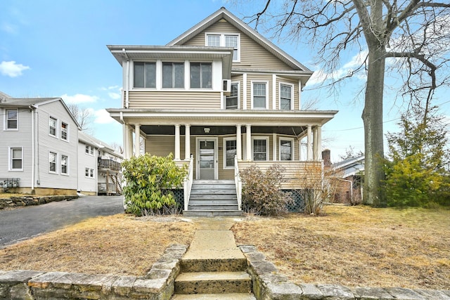 american foursquare style home featuring aphalt driveway and a porch