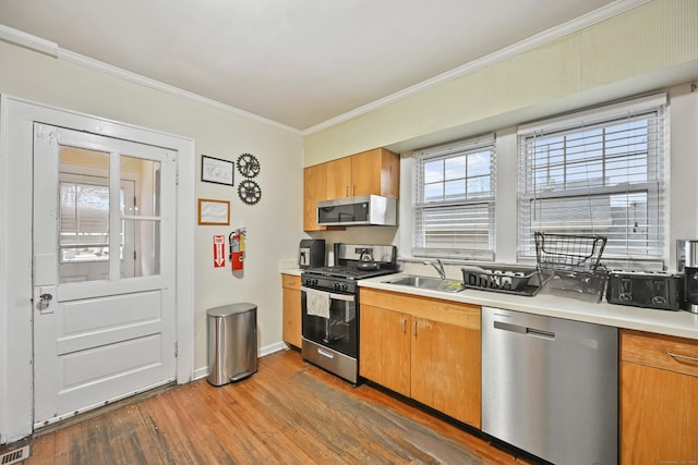 kitchen with dark wood-style flooring, a sink, stainless steel appliances, light countertops, and crown molding