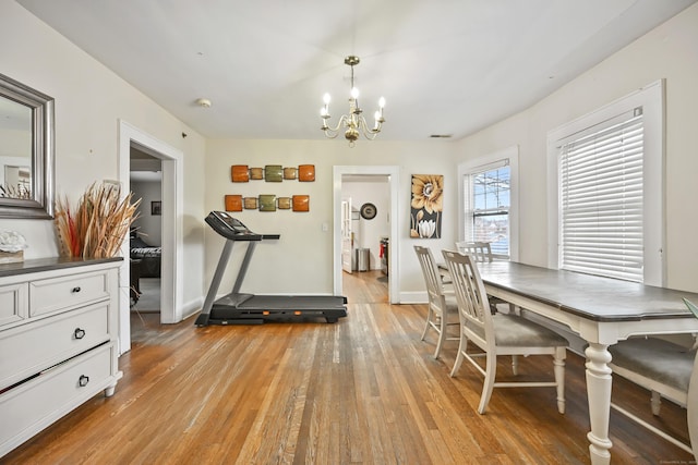 dining room featuring a notable chandelier, baseboards, and light wood finished floors