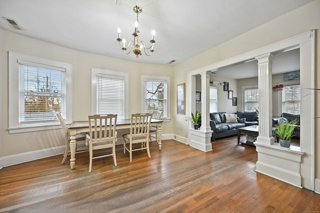 dining space with decorative columns, wood finished floors, visible vents, and baseboards