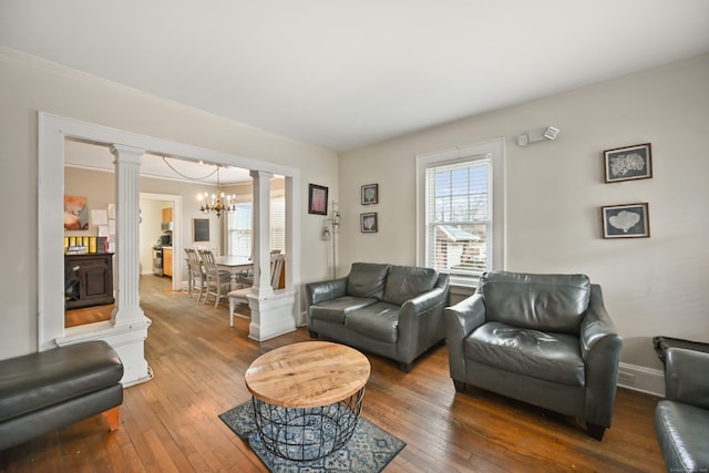 living room featuring hardwood / wood-style floors, ornate columns, and a chandelier