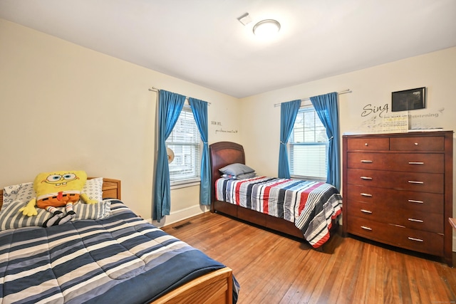 bedroom featuring visible vents, baseboards, and hardwood / wood-style flooring