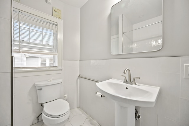 bathroom featuring a sink, tile patterned flooring, wainscoting, tile walls, and toilet