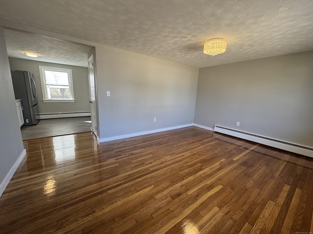 empty room featuring a baseboard heating unit, dark wood-style floors, baseboards, and a textured ceiling