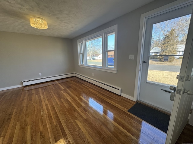 interior space featuring baseboard heating, a textured ceiling, dark wood-type flooring, and baseboards