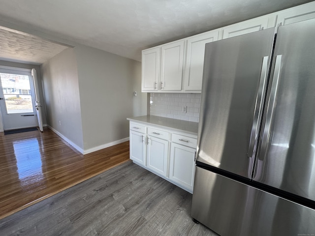 kitchen with backsplash, dark wood finished floors, freestanding refrigerator, white cabinets, and light countertops