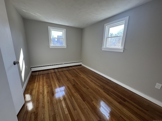 empty room featuring dark wood finished floors, baseboards, and a baseboard radiator