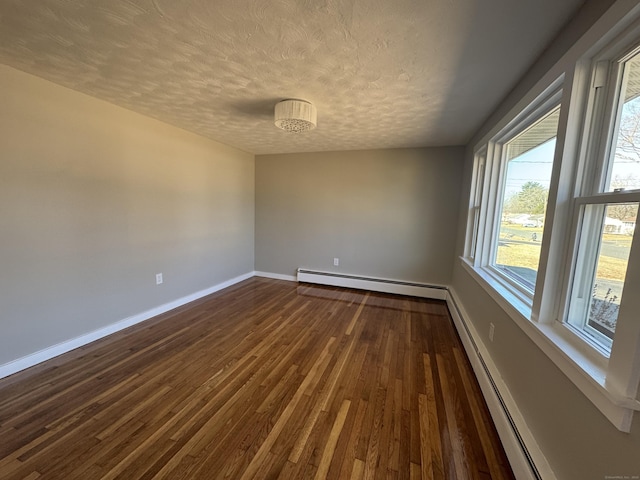 spare room with baseboards, baseboard heating, dark wood-style floors, a textured ceiling, and a baseboard radiator