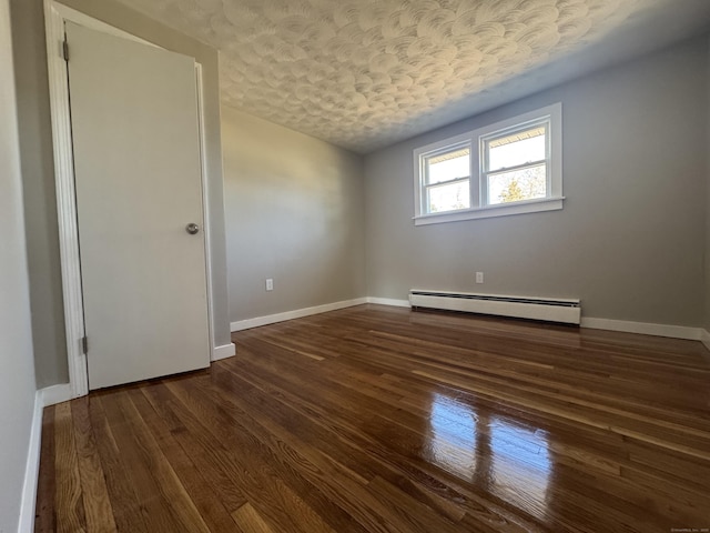 empty room featuring baseboard heating, a textured ceiling, baseboards, and wood finished floors