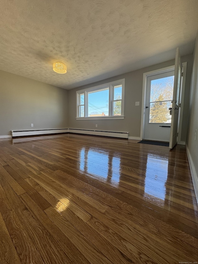 empty room featuring baseboards, a textured ceiling, and dark wood finished floors