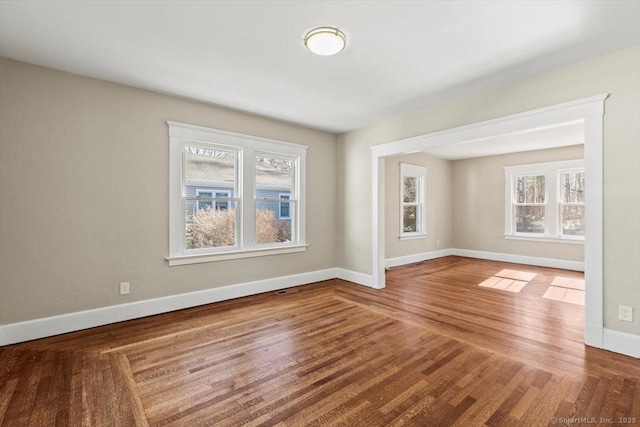 spare room with plenty of natural light, baseboards, and wood finished floors