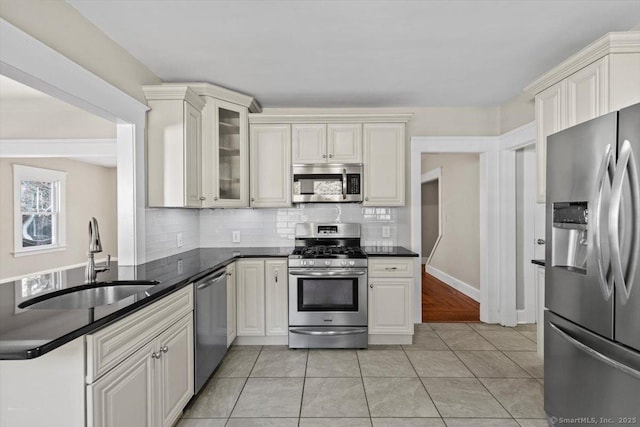 kitchen featuring appliances with stainless steel finishes, dark countertops, a sink, and decorative backsplash