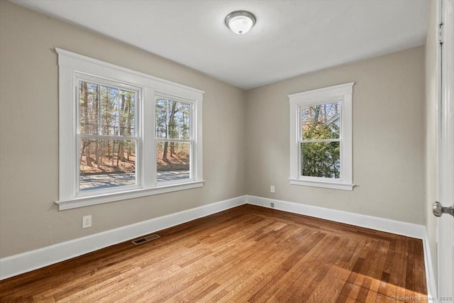 empty room featuring baseboards, visible vents, and wood finished floors