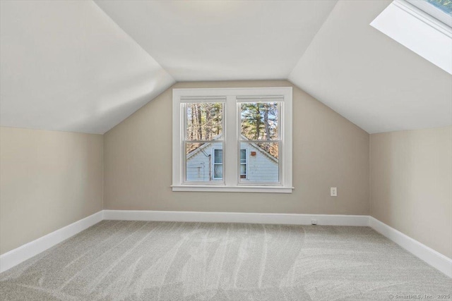 additional living space with vaulted ceiling with skylight, carpet flooring, and baseboards