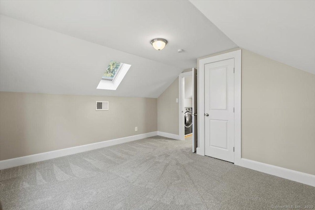 bonus room with light carpet, baseboards, vaulted ceiling with skylight, and visible vents