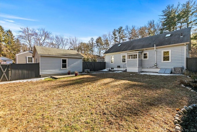 back of house with an outbuilding, a lawn, and fence