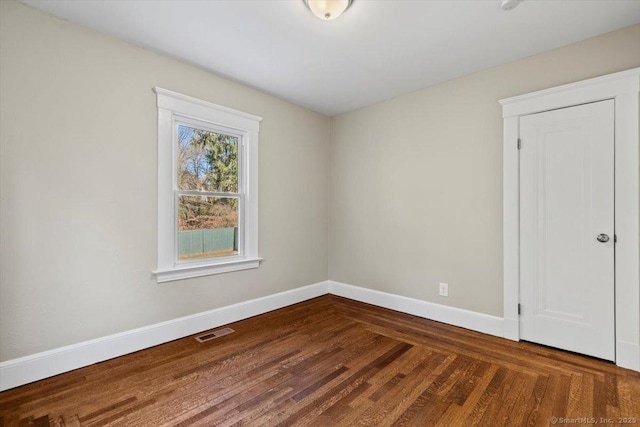 empty room with visible vents, baseboards, and wood finished floors