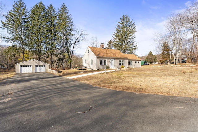 view of front of property with an outbuilding, a chimney, and a detached garage