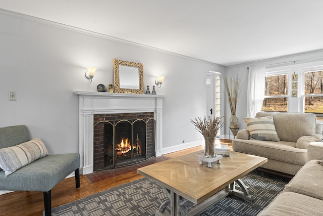 living room with wood finished floors, crown molding, a fireplace, and baseboards