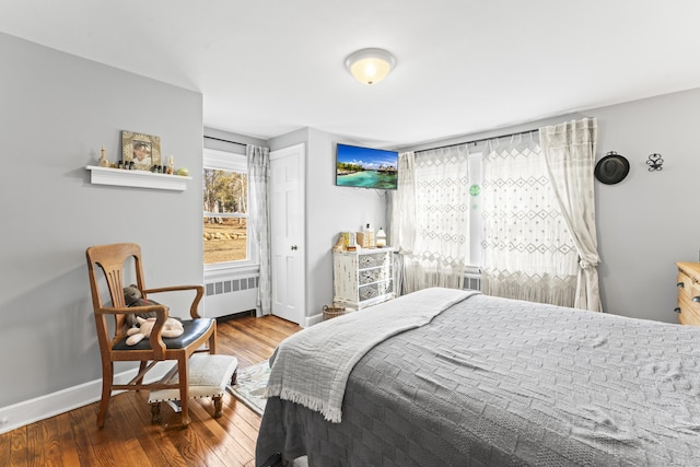 bedroom featuring radiator heating unit, wood finished floors, and baseboards