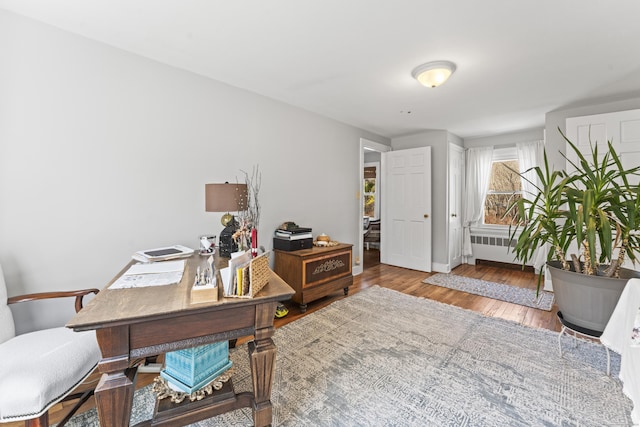 office area with radiator, wood finished floors, and baseboards