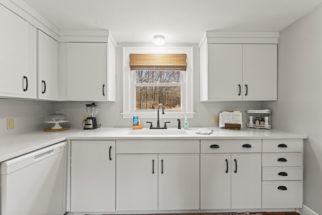 kitchen with a sink, white cabinets, white dishwasher, and light countertops