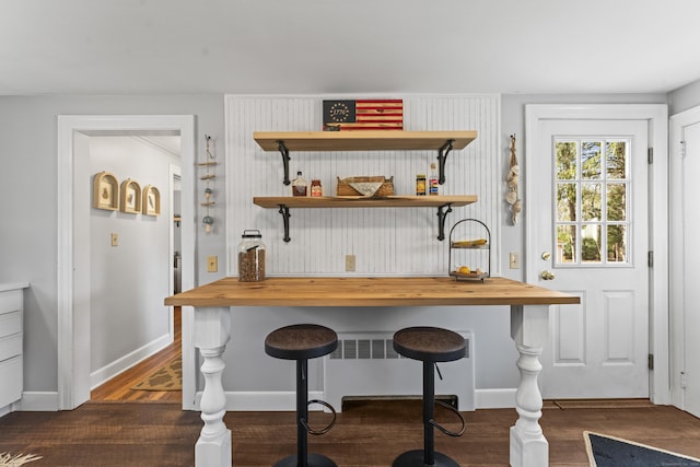 bar featuring radiator heating unit, baseboards, and dark wood-style flooring