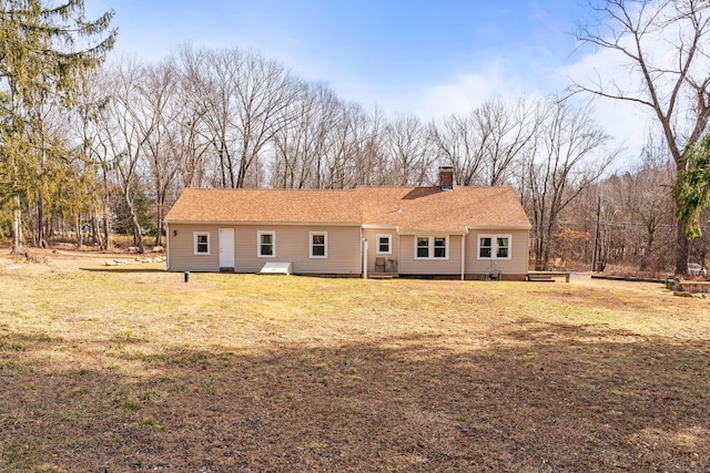 view of front of home with a chimney, a front lawn, and a shingled roof