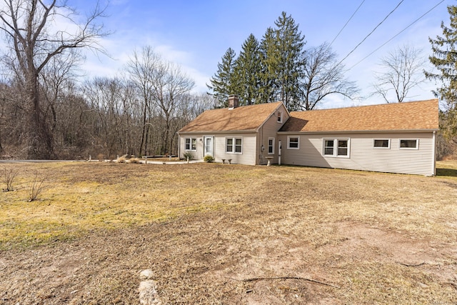 back of property with a chimney and roof with shingles